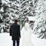 bride and groom walking in snow cover trees