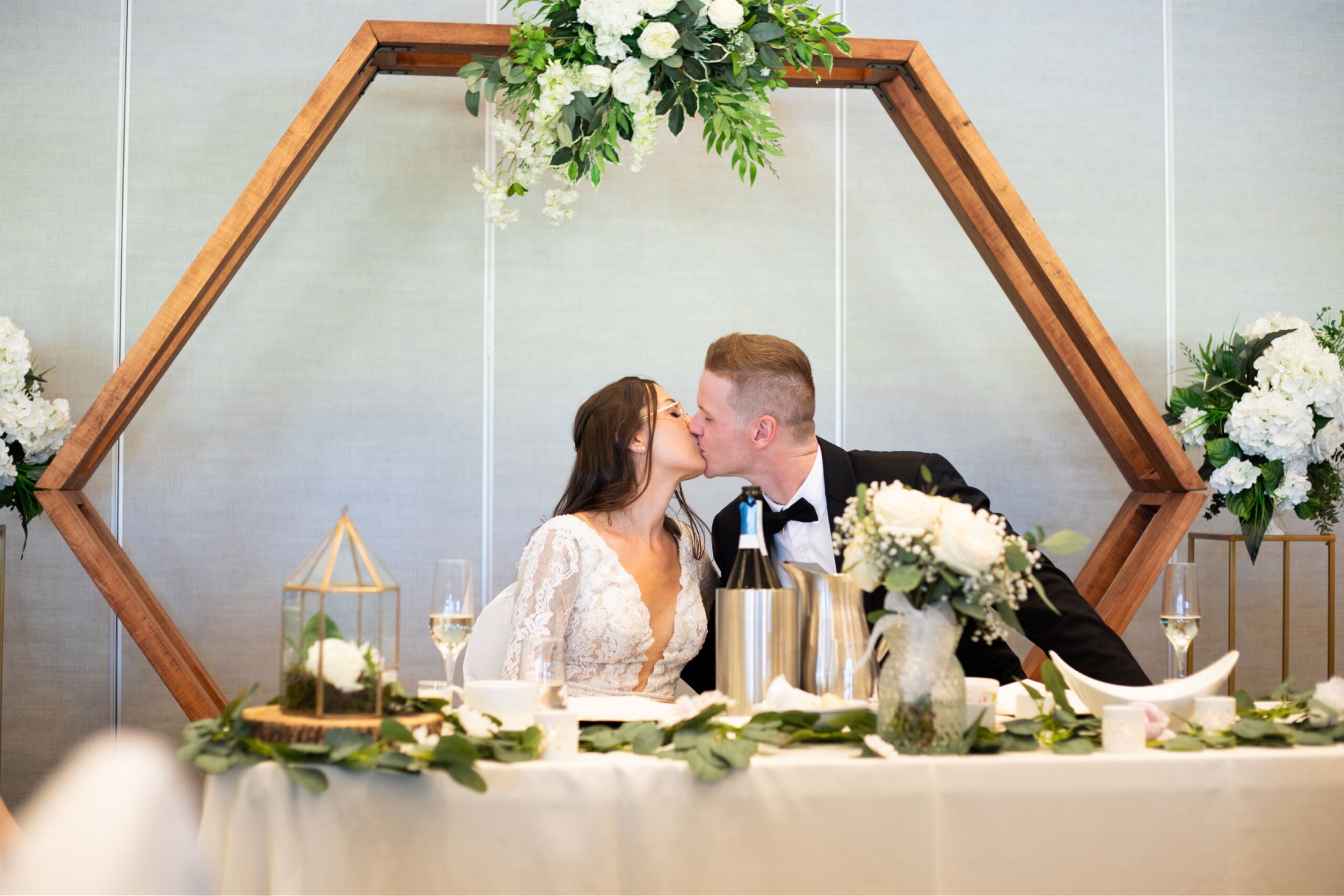 couple kisses at head table