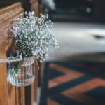 Mason jar with baby's breath tied to wooden pew