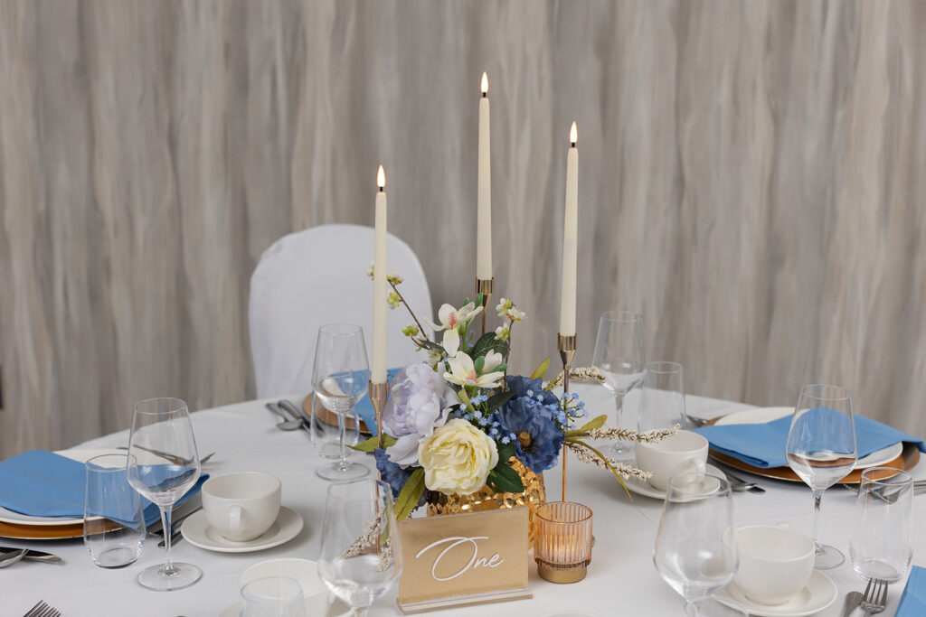 Styled wedding table with candles, floral centrepiece, and blue linens